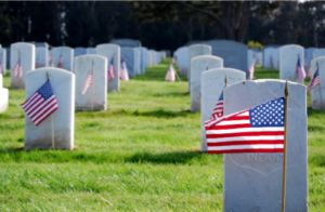 Military cemetery with American flags at each gravestone.