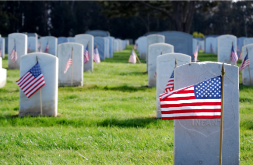 Military cemetery with American flags at each gravestone.